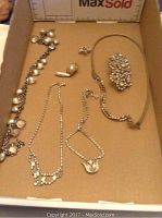 Overall view of six pieces of rhinestone jewelry including necklaces, brooch, and pin laid out in a box.