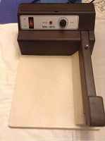 Full view of Hulme-Martin sealing machine showing handle and flat sealing area.