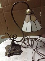 Full view of Tiffany style desk lamp showing stained glass shade and curved metal arm attached to metal base with switch and power cord.