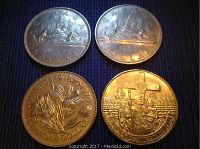 Four Canadian dollar coins dated 1968, 1969, 1970, and 1984 displayed on dark fabric, showing both obverse and reverse sides.