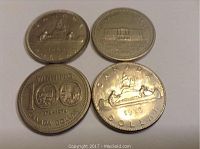 Four Canadian dollar coins laid flat showing obverse and reverse sides and details of each design.