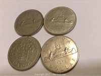 Four silver-colored Canadian dollar coins featuring Voyageur design, showing obverse and reverse sides, dated 1968, 1969, 1971 BC, and 1972