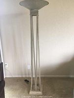 Full view of the tall Grecian style floor lamp showing thin metal vertical supports and square marble base.