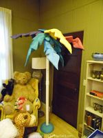 Full view of fabric tropical tree in two pieces including base and colorful leaves detail.