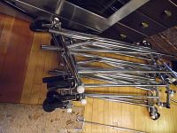 Stacked metal garment racks showing chrome tubular frames and caster wheels on wood flooring.