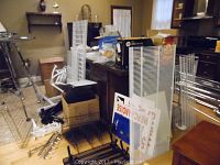 Various metal display shelves and grids leaning against furniture and stacked on floor indoors.