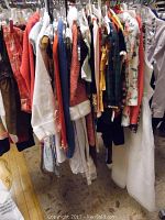 Photo of children's clothing hanging on rack including various dresses, sweaters, and tops showing the range of colors and styles.