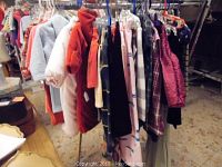Hanging assorted children's clothing on rack showing various styles, colors, and types including jackets and sweaters
