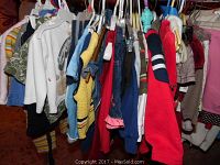 Clothes hanging on a rack showing assorted boy and girl clothing with various colors and styles.