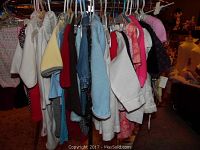 Photo showing multiple children's clothing items hanging on a rack, mixed colors and styles including sweaters, jackets, and shirts