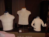 Three child mannequins in varying sizes, fabric covered with bases, displayed on a table.