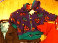 Purple fleece jacket with animal pattern, brown jacket, and red garment laid out on floor