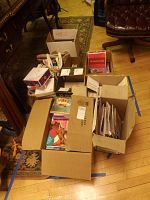Multiple cardboard boxes filled with over 50 children's and young adult books and magazines including American Girl publications.