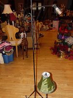 Photo showing the two metal lamps in a room with various other items in the background, the floor lamp with an adjustable arm and the table lamp with a green fabric shade.