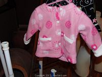 Pink fleece jacket with flower patterns displayed on hanger