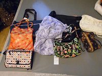 All five diaper bags displayed on a table showing a variety of styles and colors.