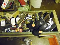Overview of over 20 pairs of used children's shoes in a container, showing a wide variety of styles and colors including sandals, slip-ons, and lace-ups.