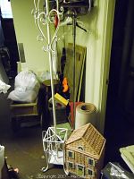 Full view showing white metal coat rack and dollhouse hamper on floor