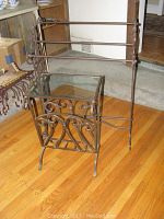 Both iron furniture pieces shown together: a quilt rack and a magazine rack with glass top on hardwood floor.