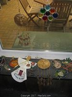 Sun catchers hanging on window and laid on black surface showing a variety including round suns, balloons, and dangling fish shapes.