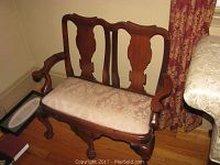 Front view of child's wooden settee showing brocade upholstered seat, claw feet legs, and carved wood details.