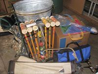 Photo showing entire set including galvanized metal beverage ice bucket, croquet mallets and balls, golf club bag, and other items in background.