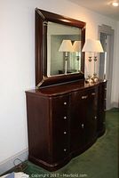 Photo of dark wood Bernhardt dresser with veneered decorative top, nine drawers and central cabinet. Large rectangular mirror mounted on top. Two lamps on dresser.