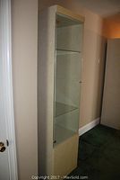 Side view of the laminate display cabinet showing solid lower door and upper glass door with glass shelves inside.