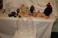 Wide view showing the assortment of antique dolls including baby dolls and the 1930s Kewpie doll along with a pair of glass display domes.