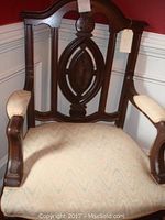 Front view of vintage wooden side chair showing upholstered seat and armrests, carved backrest detail