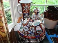 Group shot of stacked plates, saucers with cups, mugs, teapot, sugar bowl and pitcher