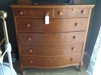 Front view of wooden dresser showing six drawers with round knobs and minor veneer chip on top full drawer.