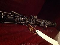 Full-length view of flute on wooden shelf showing body and key mechanism