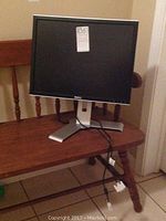 Front view of Dell monitor on a wooden bench showing screen, bezel and stand.