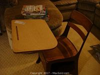 Vintage metal school desk with wooden seat and backrest shown with attached wooden desktop and a collection of home school teaching books stacked nearby.