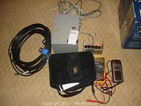 View showing two handheld GPS units, Fluke multimeter, Cypher lock control box, and multiple cables on carpeted floor.