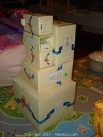 Stacked original Winnie the Pooh collectible boxes in cream colored packaging tied with blue ribbons