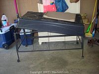Front and side view of black metal wire rabbit cage with plastic base and wheels. Cage is rectangular measuring approximately 47x24x26 inches.