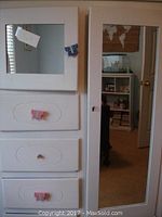 Front view of the dresser showing the mirrored door and drawers with butterfly-shaped knobs in various colors.