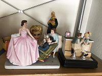 Photo showing multiple figurines including the Sweet Sixteen Norman Rockwell porcelain figurine prominently in pink and other figurines like the Virgin Mary and soda fountain children.
