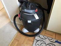 Front view of the Shop-Vac wet dry vacuum showing the tank, hose coiled around, and base with caster wheels.