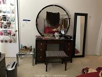 Wide view showing the full vanity, round mirror with lights, and bench in a room setting.