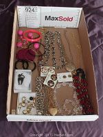 Full view of assorted costume jewelry including necklaces, earrings, bangles, and brooches arranged in a cardboard box