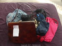 Dark brown structured handbag, black macrame clutch, pink fabric tote, blue drawstring bag clustered together on a bed.