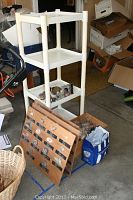 Photo of plastic white 3-tier shelving unit holding various mineral specimens and onyx figurines, along with three wooden mounted display boards and bags nearby.