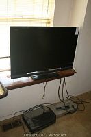 Sony 42 inch Bravia TV set on a window ledge with cables and remote.