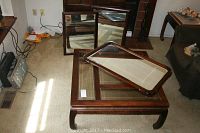 Wood and glass coffee table with three large mirrors placed on top of it in a living room setting