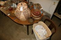 Photo showing five woven baskets placed on a table, including one large lidded basket with a tag, and four smaller baskets of varying shapes and designs.