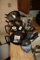 Overhead view of the countertop with cast iron skillets, pots, pans, various trivets, and a roaster arranged together including a note describing contents.