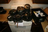 Calphalon cookware items displayed on stove, including various pots and pans, some with lids, showing size and condition.